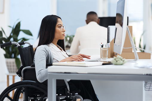 An image featuring a woman in a wheelchair working in an office
